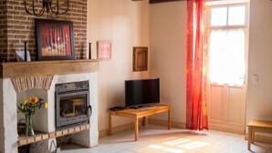 A living room with a fireplace, television, and a window with red curtains. - Homerez - Villa in Issac (Issac)