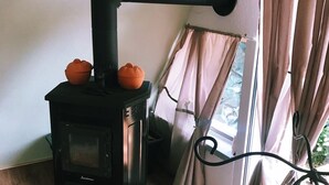 A wood-burning stove with two orange pots on top, a curtain rod, and deer antlers on the wall. - Little break (Gossersweiler-Stein)