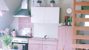 A modern kitchen with a wooden dining table, chairs, and a wooden ladder. - Little break (Gossersweiler-Stein)