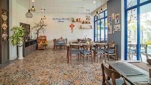 A dining area with patterned floor tiles, wooden furniture, and decorative wall art. - Blue Boutique Villa Hoi An (Da Nang)