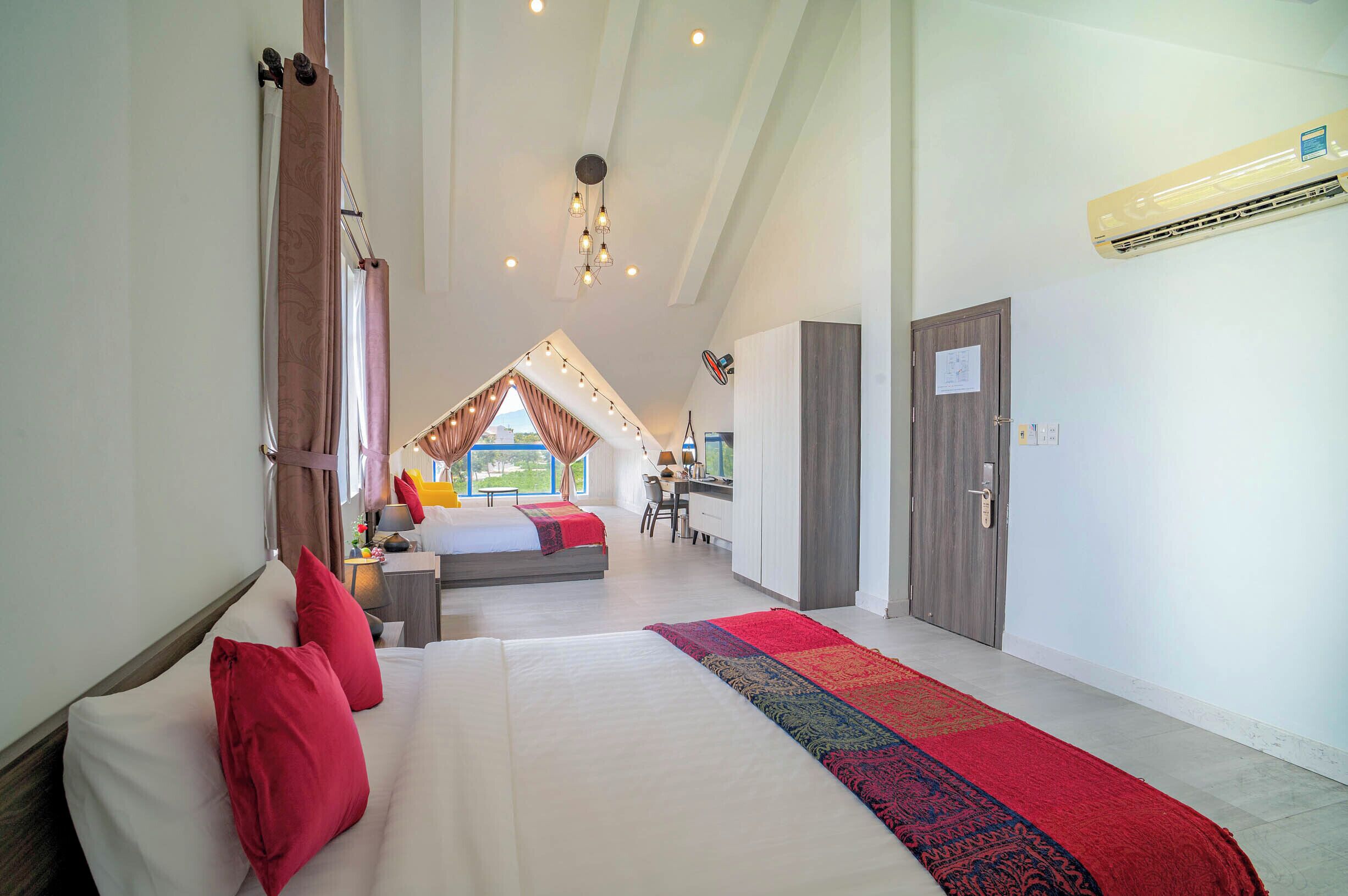 Amplia habitación de hotel con una cama grande, un escritorio y vistas al exterior.