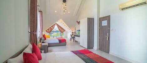 Amplia habitación de hotel con una cama grande, un escritorio y vistas al exterior.