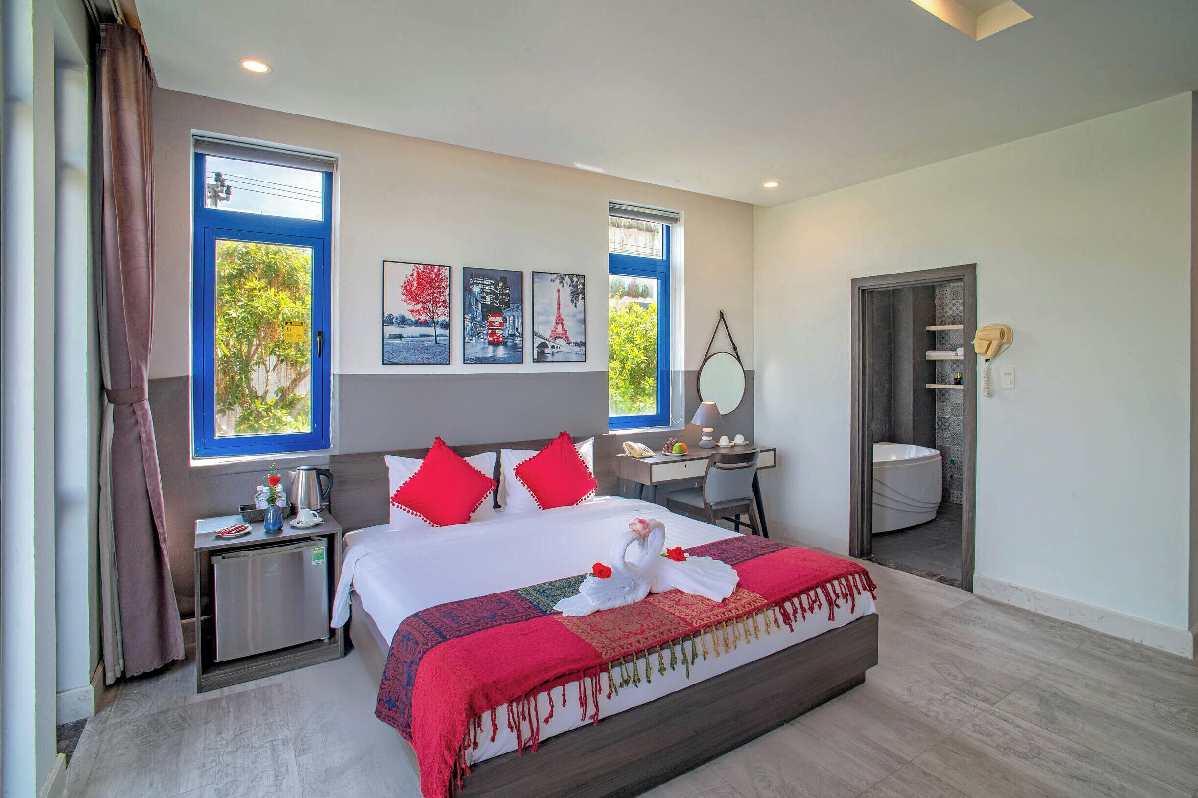 A hotel room with a bed, desk, and shower.