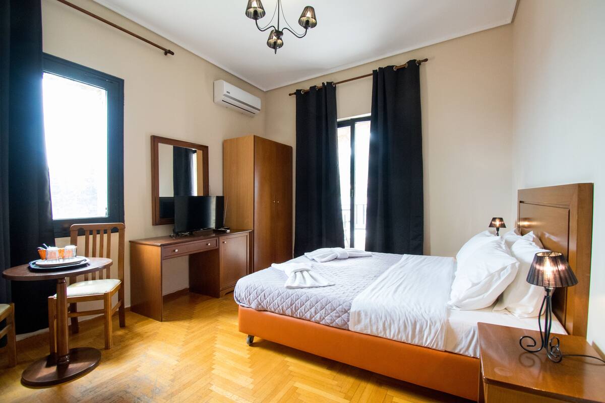 A hotel room with a bed, desk, chair, and a television.