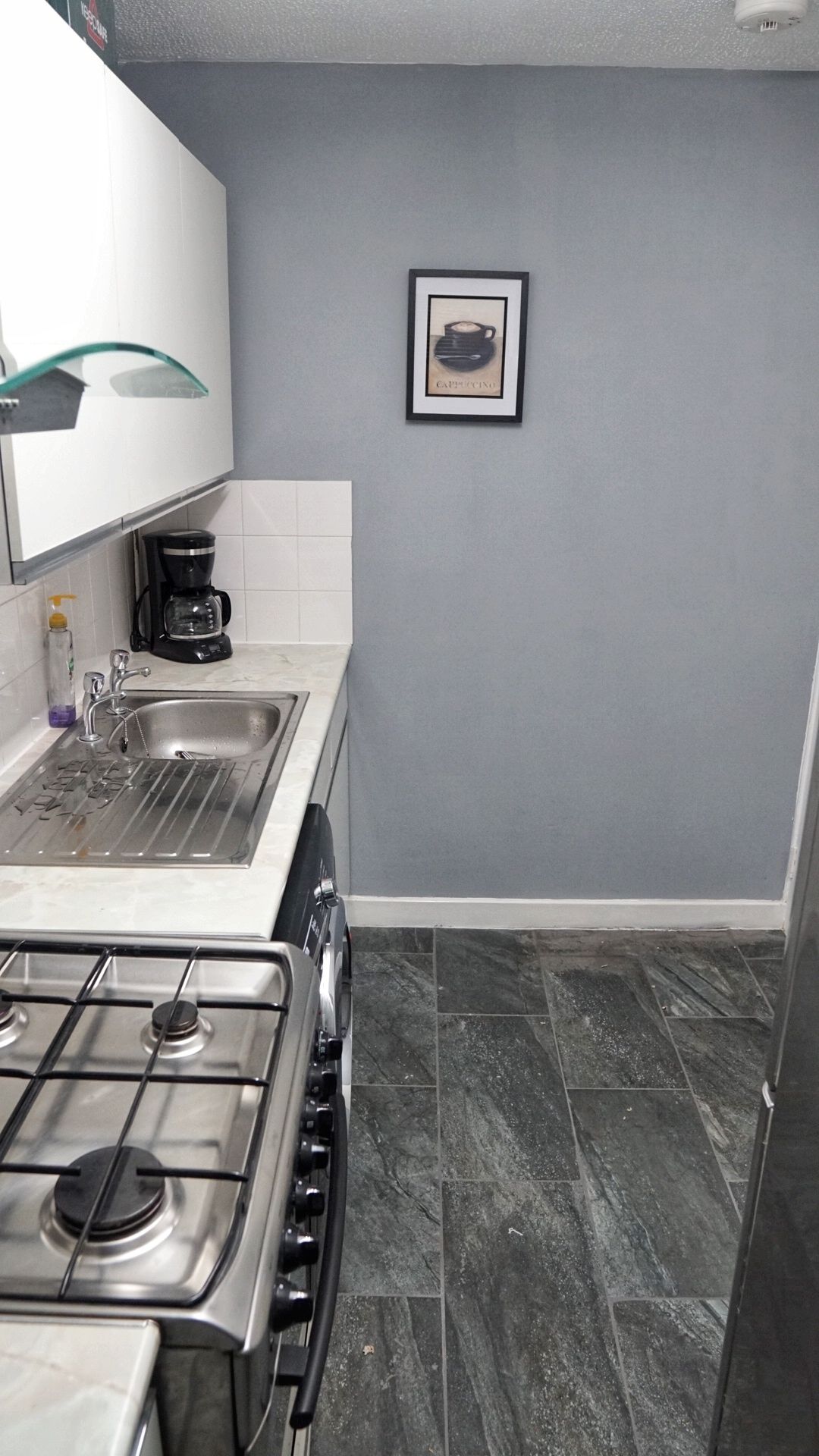 A kitchen with a gas stove, a sink, and a coffee maker.