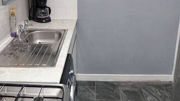 A kitchen with a gas stove, a sink, and a coffee maker.