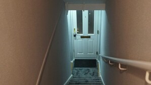 A carpeted stairway leading to a white door with a small window above it. - North London Apartment - Edmonton (London)