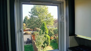 A window with a view of a garden, a wooden fence, and a tall tree. - North London Apartment - Edmonton (London)