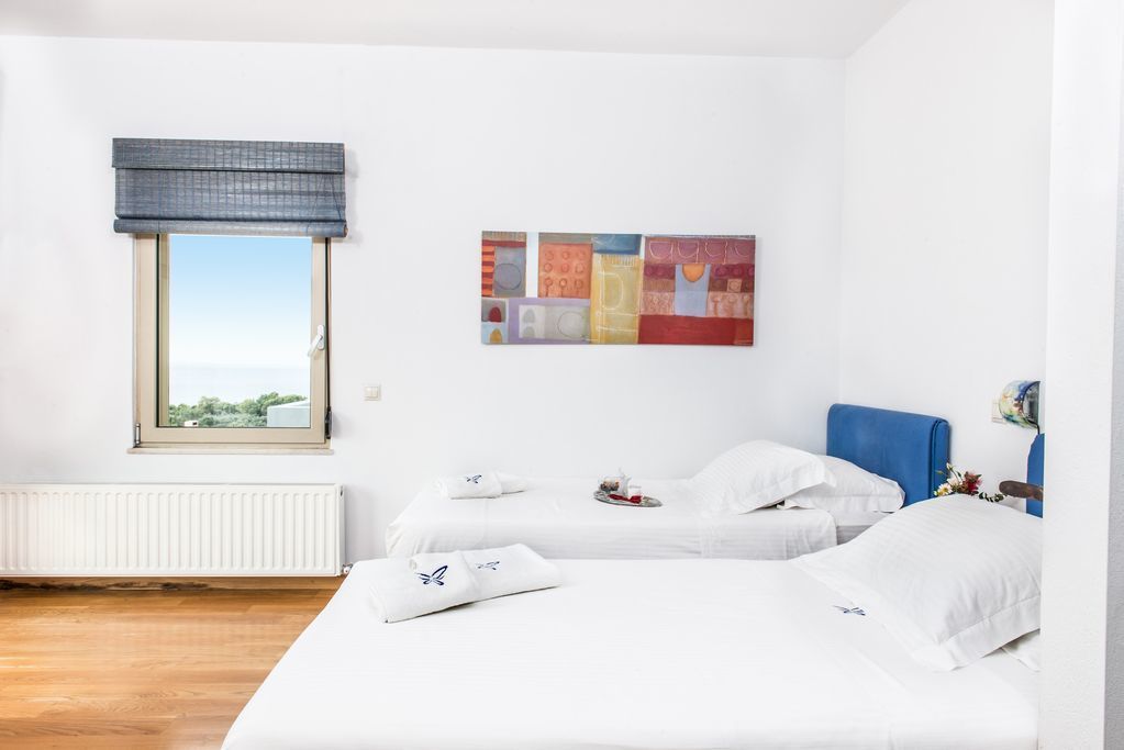 A hotel room with two beds, a window with a view, a radiator, and a wall with colorful artwork.