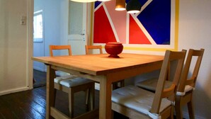 A dining area with a wooden table and chairs, a red vase, and a colorful wall mural. - Schöne 3Zimmer FeWo direkt am Baalensee (Fürstenberg-Havel)