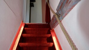 A staircase with red carpeted steps and a rope handrail. - Schöne 3Zimmer FeWo direkt am Baalensee (Fürstenberg-Havel)