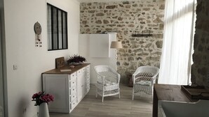 A room with a stone wall, white furniture, and a wooden floor.