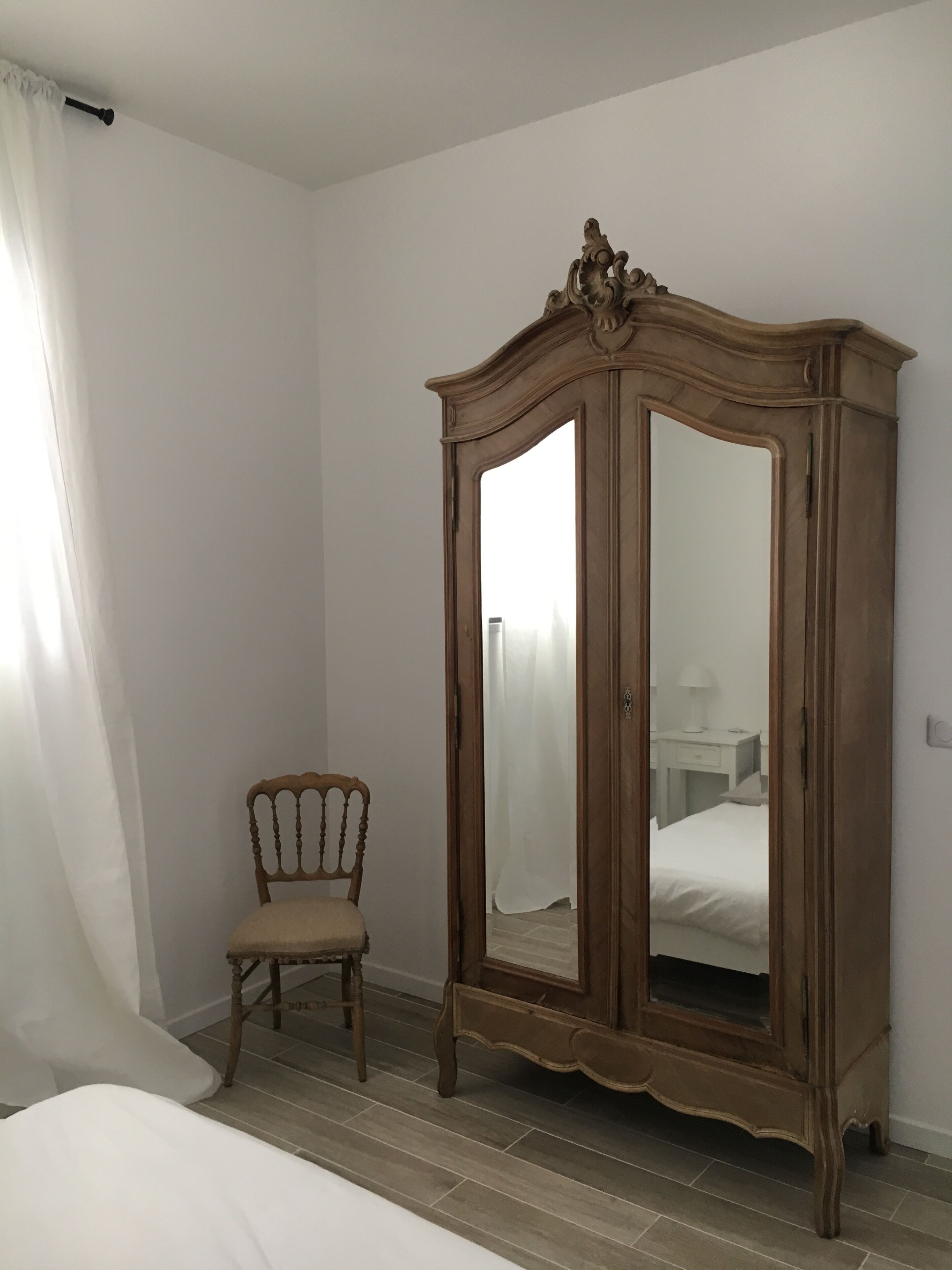 Un dormitorio con un armario de madera, una silla de madera y una cama.