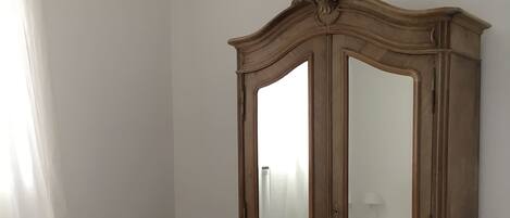 Un dormitorio con un armario de madera, una silla de madera y una cama.