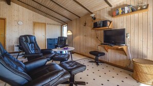 Een gezellige woonkamer met lederen fauteuils, een televisie op een houten dressoir en een boekenkast.