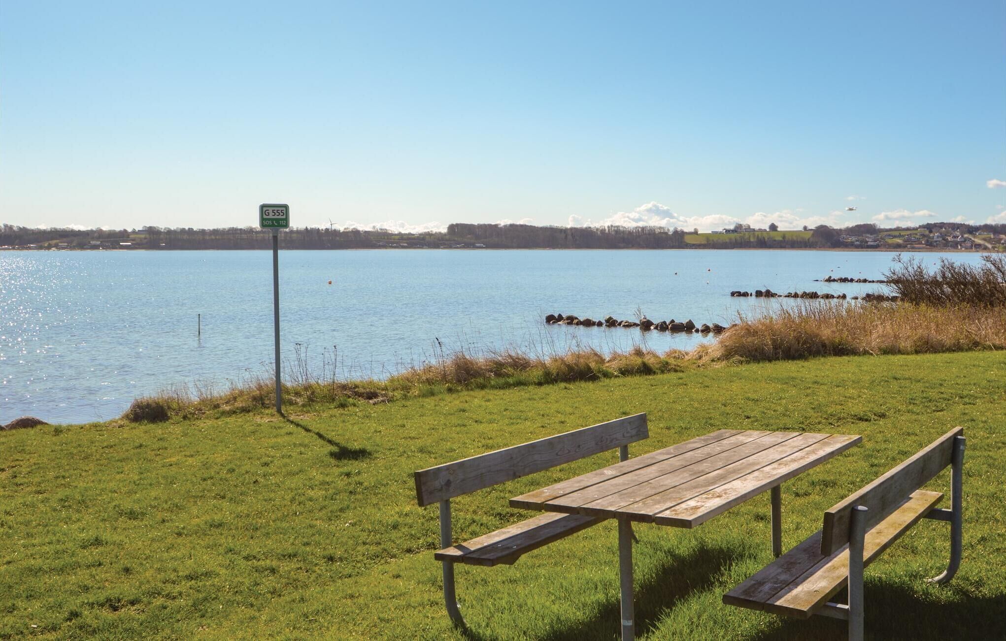 A lakeside picnic area with a bench and a signpost.
