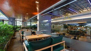 A modern restaurant with wooden ceiling, green seating, and a view of the outdoor area. - Aspira One Sutthisan (Bangkok)