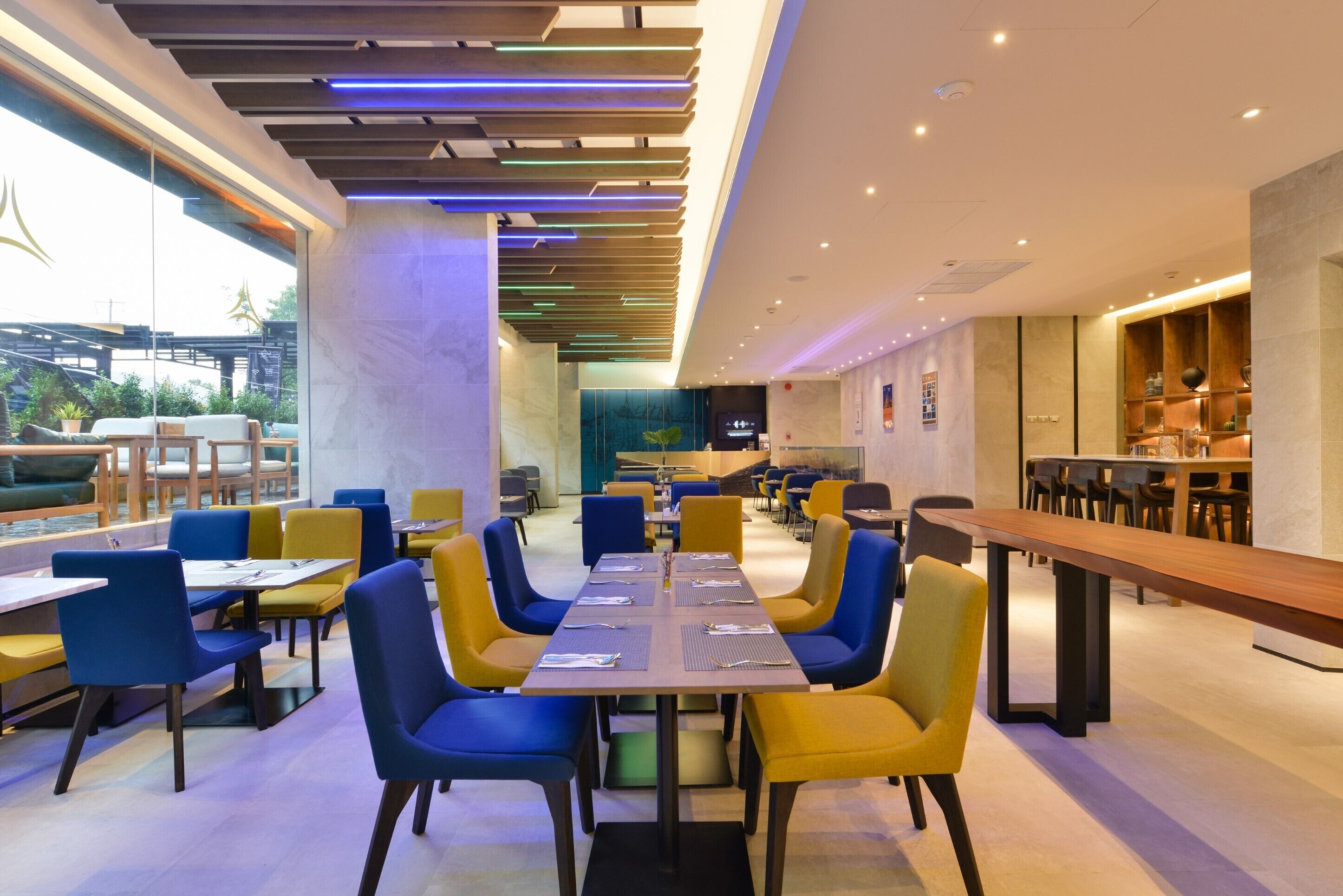 A modern dining area with a long table and chairs, a bar area, and a view of the outdoors.