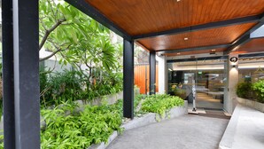 A covered entrance with a wooden ceiling, a glass door, and a pathway leading to a building. - Aspira One Sutthisan (Bangkok)