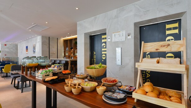 A buffet setup with various food items and a wooden display case. - Aspira One Sutthisan (Bangkok)