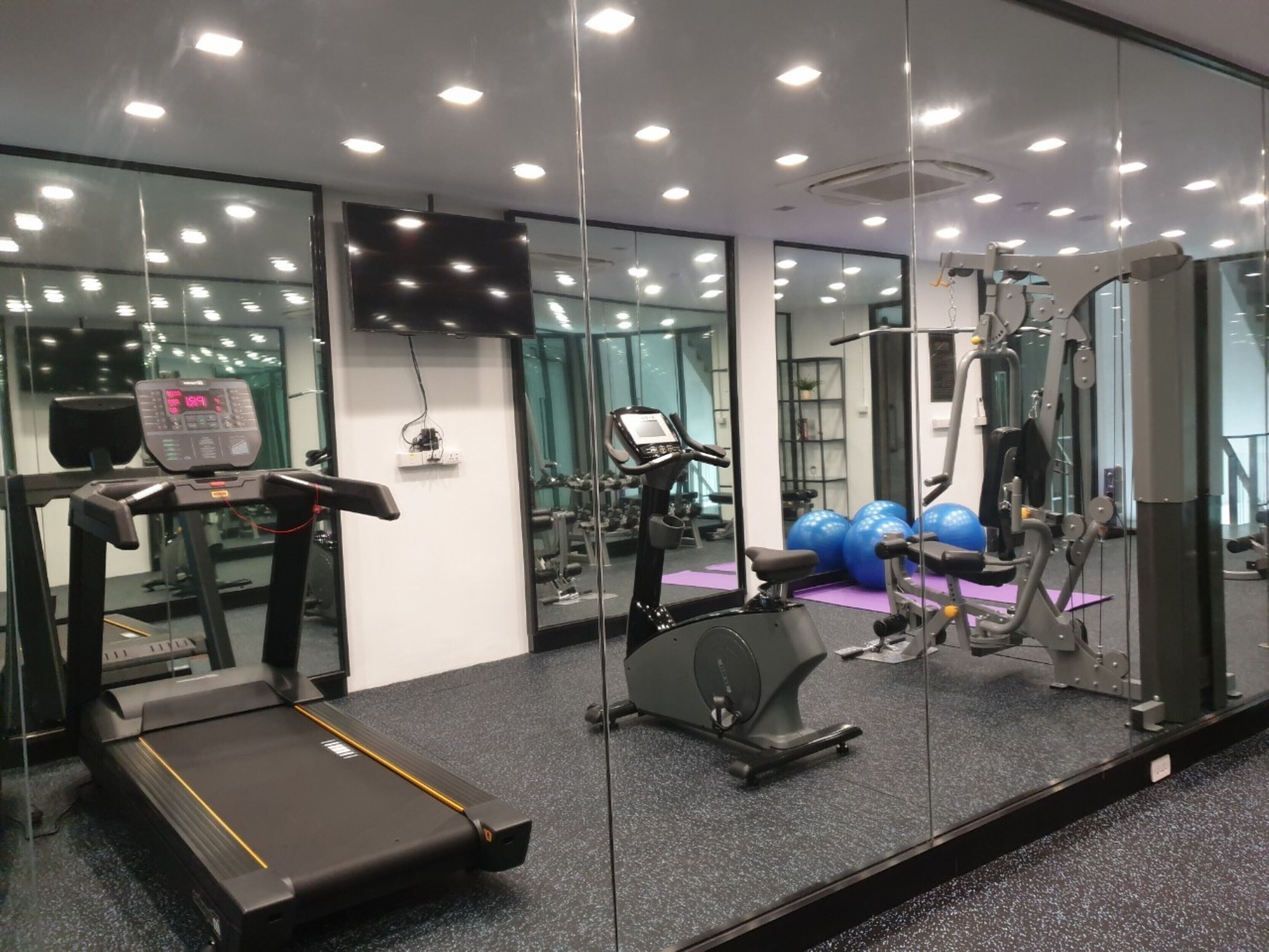 Een sportschool met loopband, elliptische trainer en gewichtstoestellen.