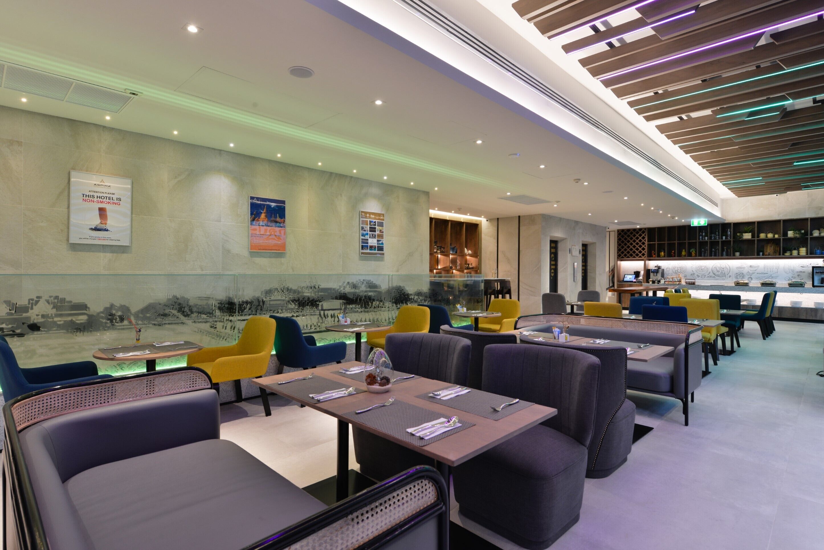 A modern restaurant with a long counter, multiple seating areas, and a view of a landscape through a large window.