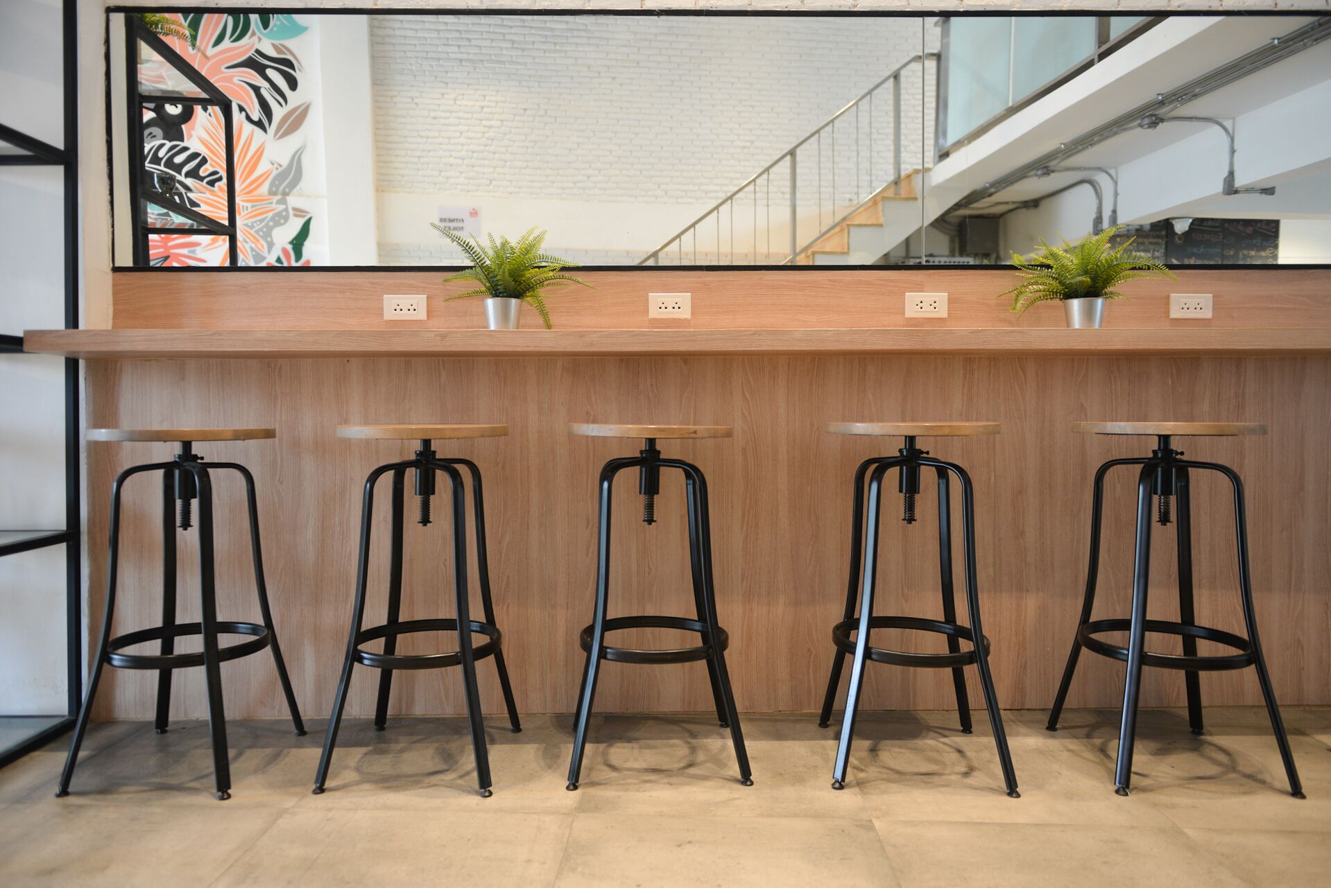 A bar area with four stools and two potted plants.