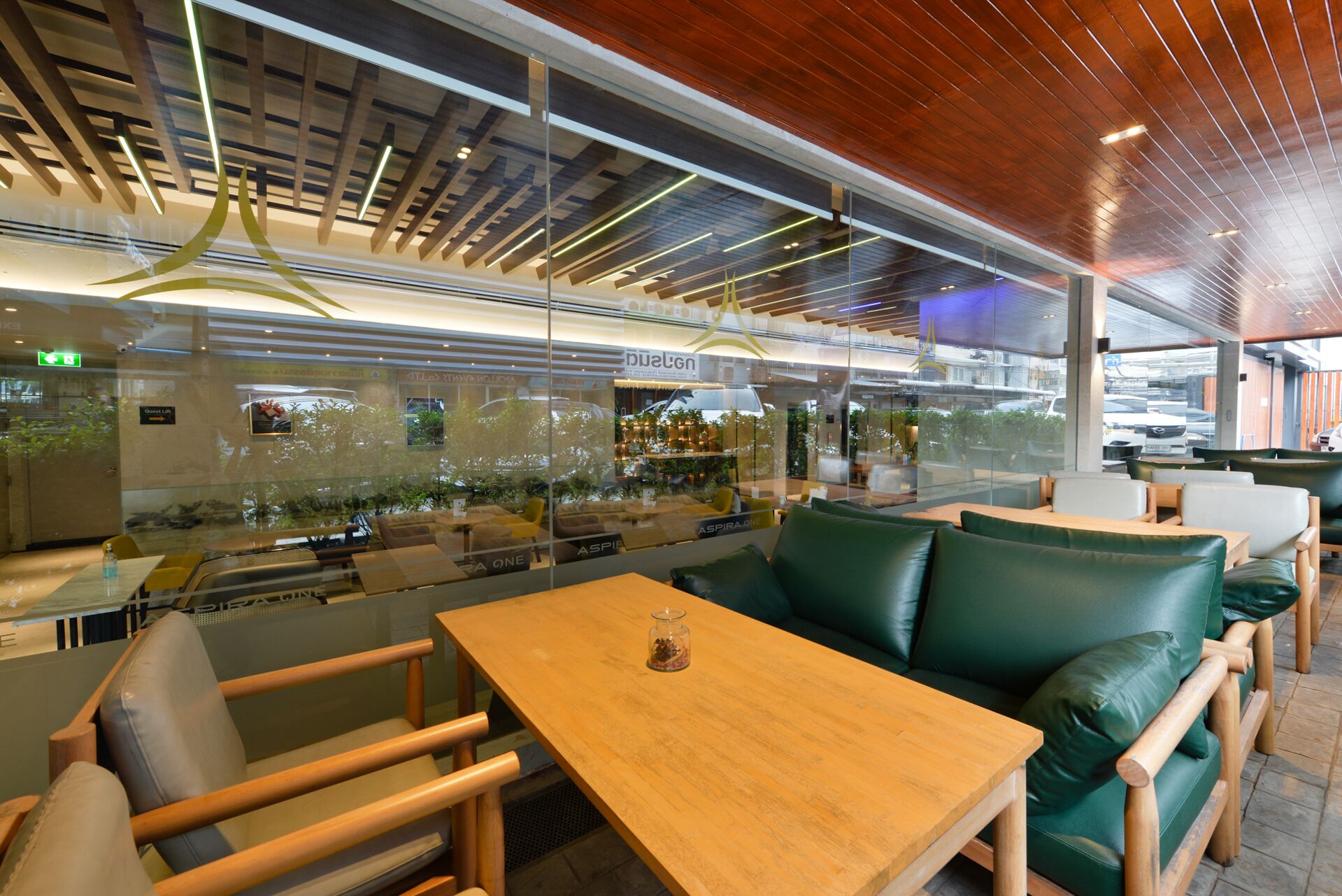 A modern restaurant interior with wooden tables and green leather seating.