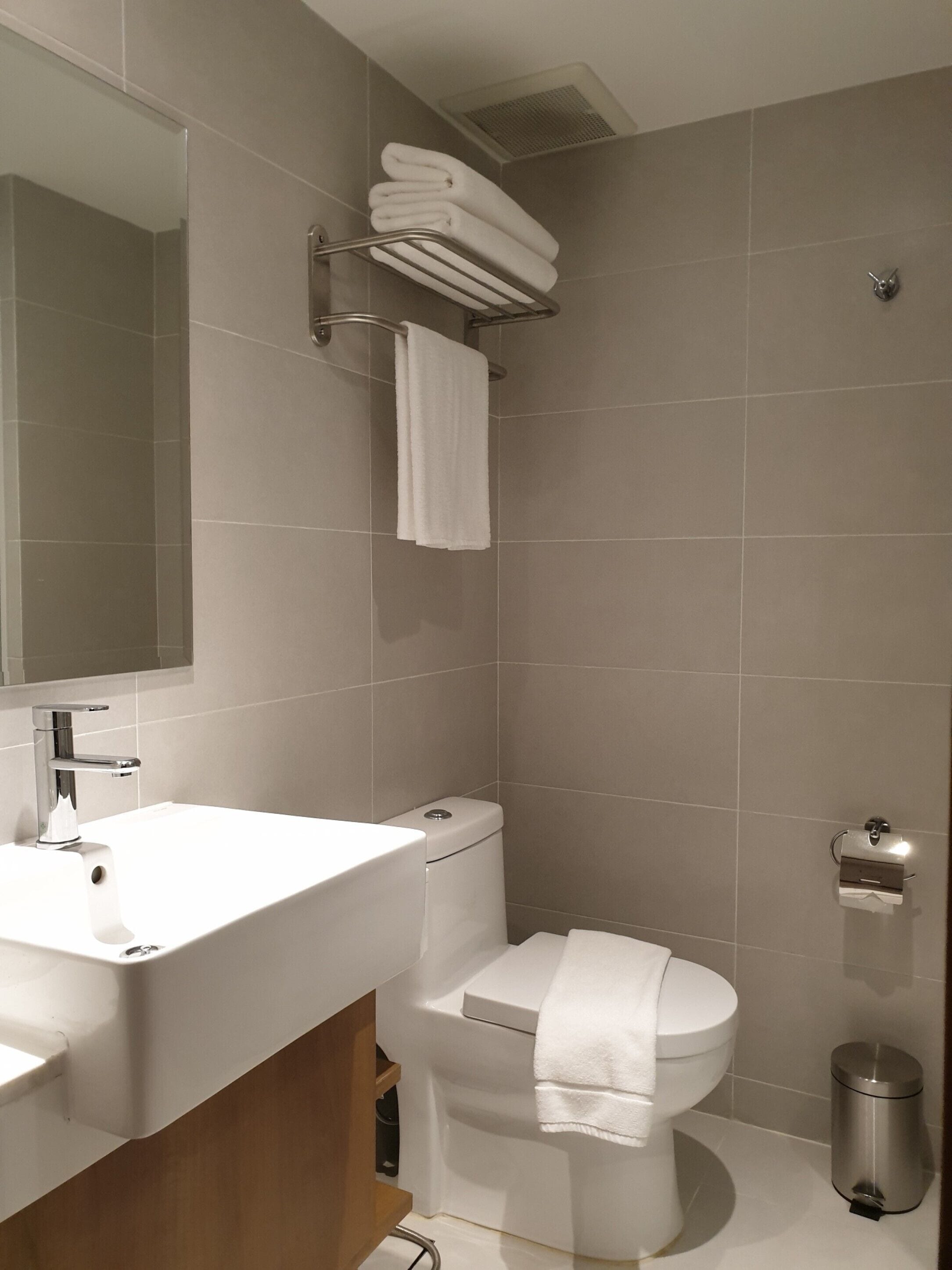 A modern bathroom with a white sink, a toilet, and a shower.
