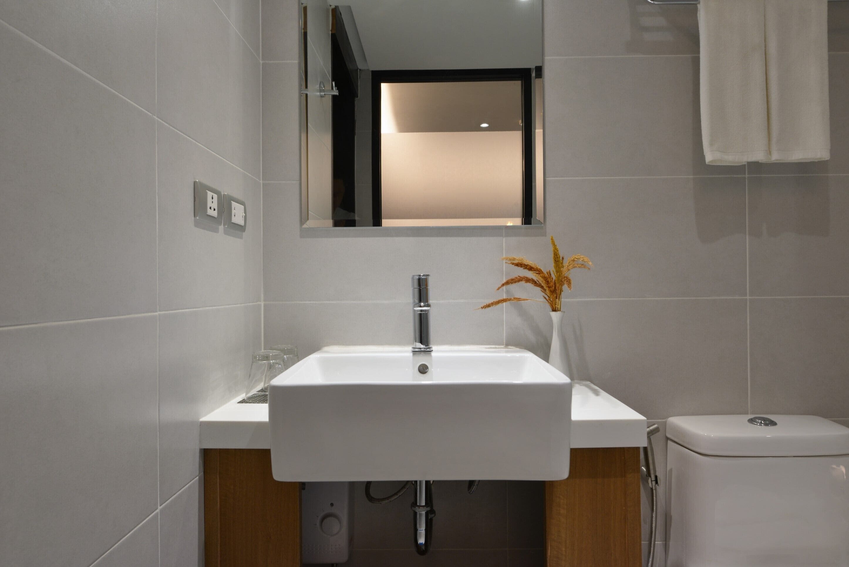A modern bathroom with a white sink, a mirror, and a toilet.