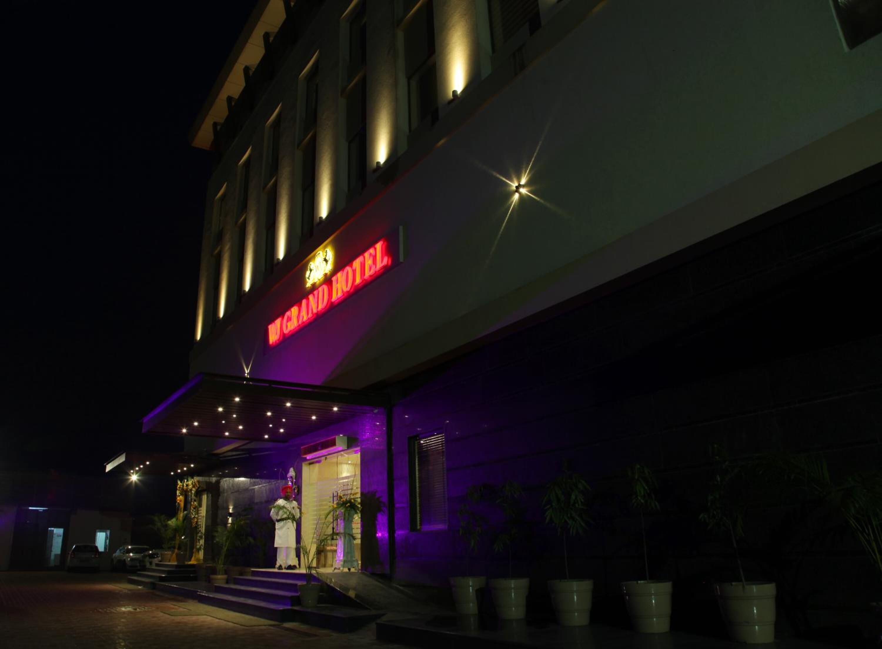 A hotel entrance with a neon sign reading "Grand Hotel".