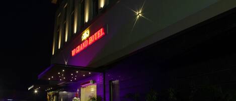 A hotel entrance with a neon sign reading "Grand Hotel".