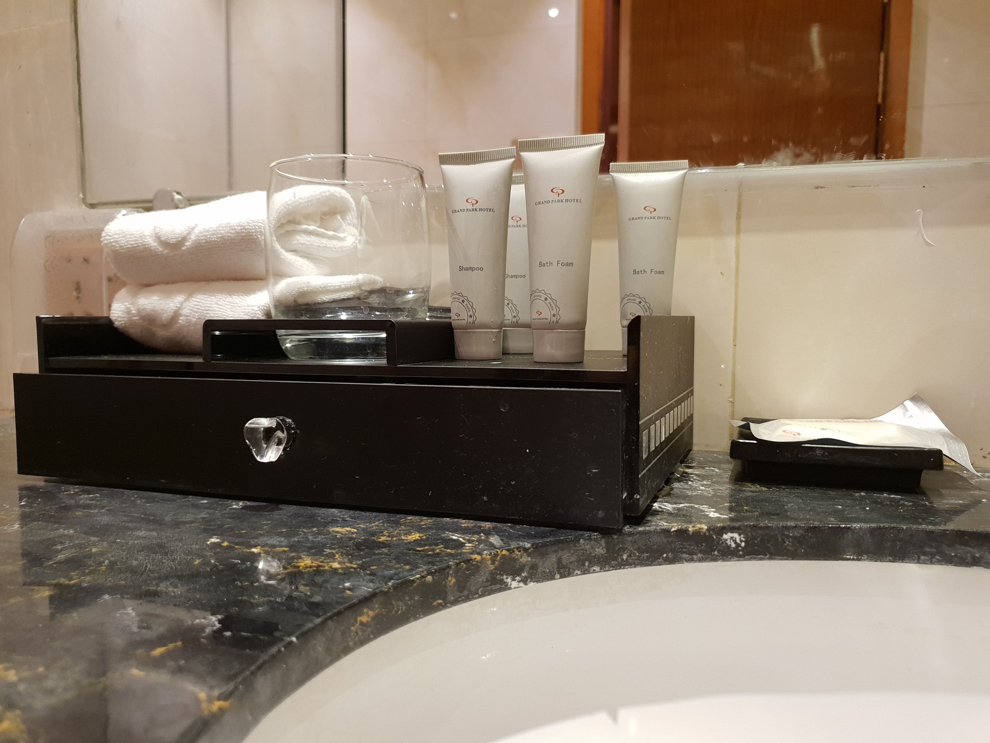 A bathroom vanity with a black tray holding toiletries, a glass, and a towel.
