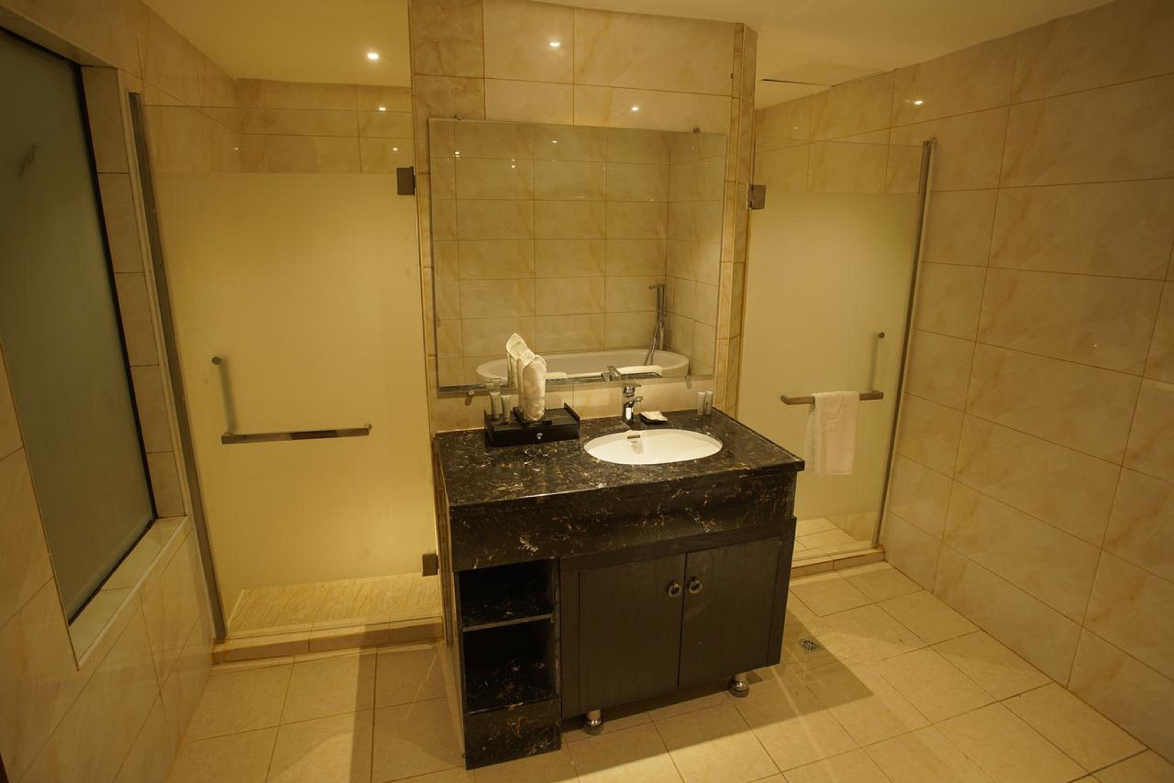 Un baño moderno con lavamanos de mármol, un espejo grande y cabina de ducha con paredes de vidrio.