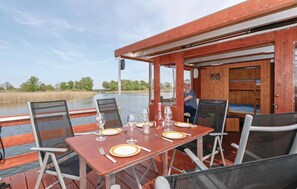 A dining table set with plates, glasses, and cutlery on a boat deck with chairs.