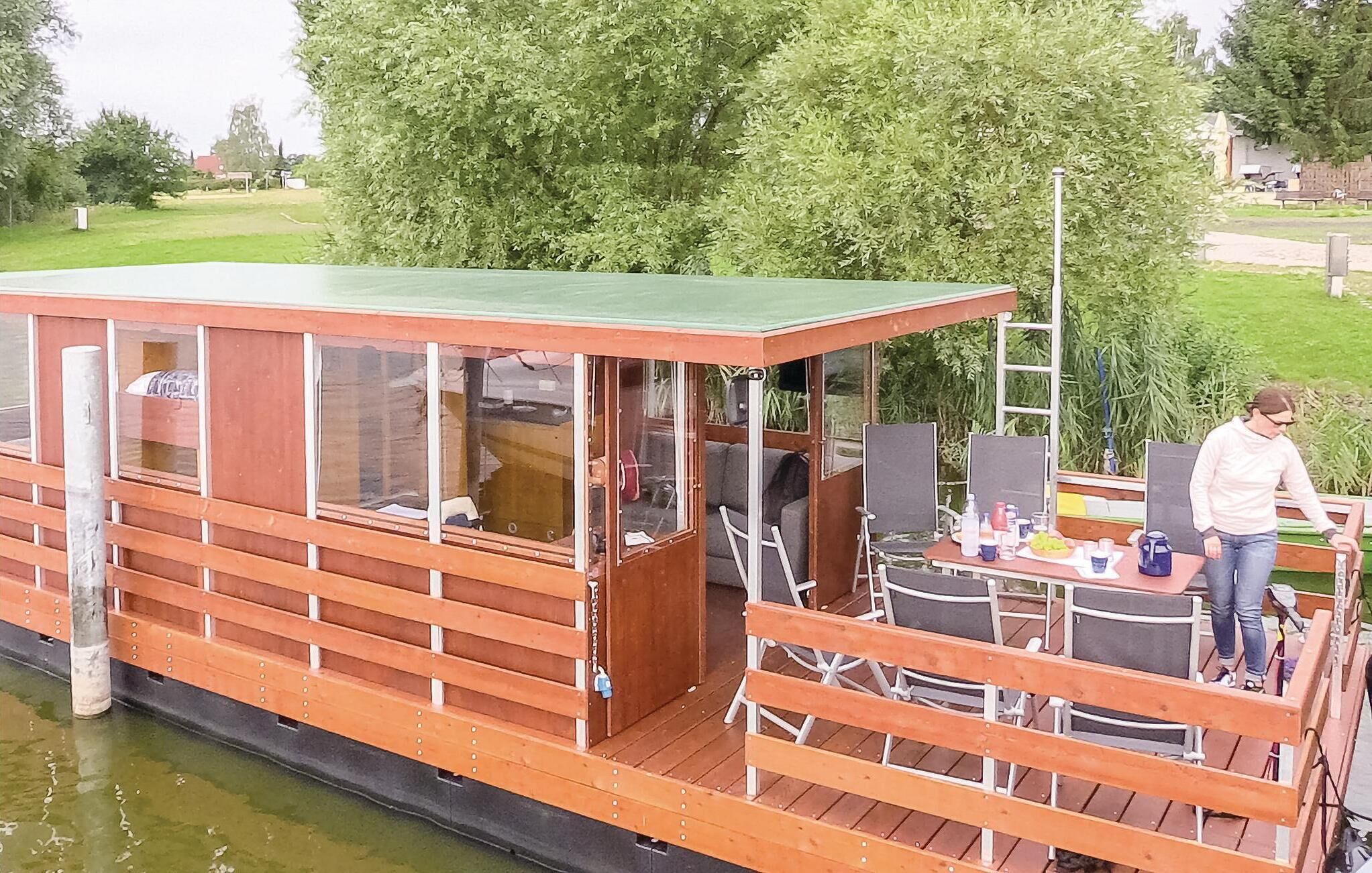 A wooden boat with a covered deck, seating area, and a table with items on it.