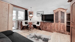 A cozy living room with a sofa, wooden cabinets, a TV, and a dining table.