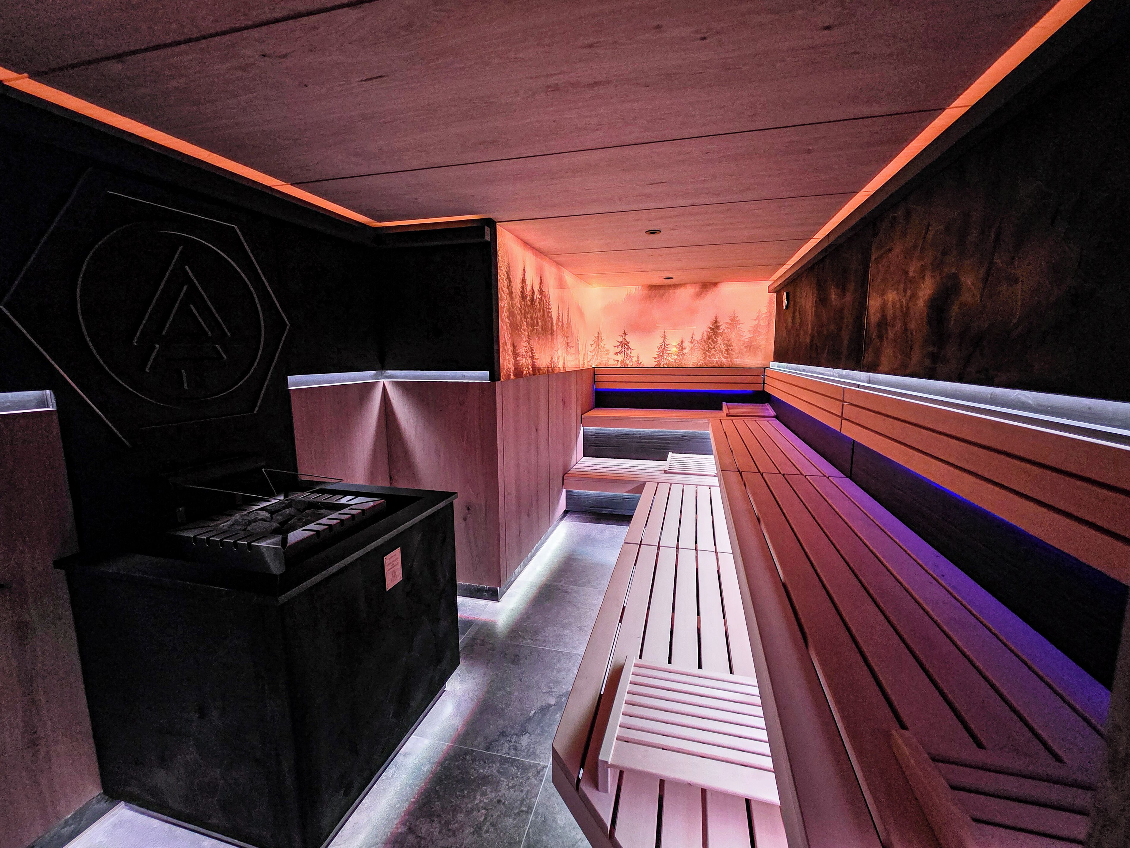 A sauna with benches and a wall-mounted heater.