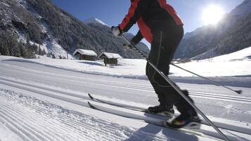 Une personne fait du ski sur une pente enneigée, avec une montagne en arrière-plan et un ciel dégagé.