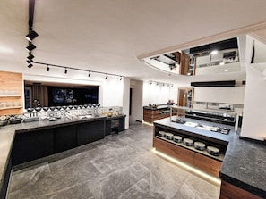 A modern kitchen with a central island, built-in appliances, and a mezzanine level with a dining area. - Hotel Lärchenhof (Kaunertal)