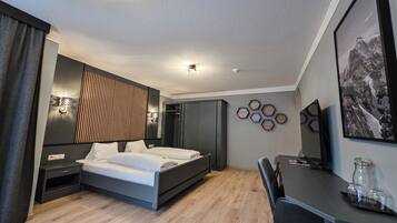 A modern hotel room with a bed, bedside tables, a desk, and a chair.
