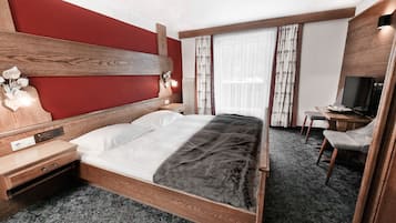 Una habitación de hotel con una cama de madera, un escritorio con una silla, un televisor y una ventana con cortinas.