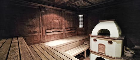 A sauna room with wooden benches and a stone heater.