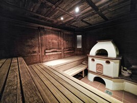 A sauna room with wooden benches and a stone heater.