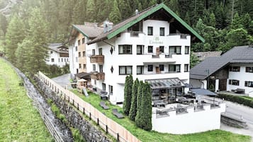 Un hotel de varios pisos con techo verde, zona de estar al aire libre y vistas a una ladera boscosa.