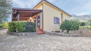 A modern two-story house with a stone-paved driveway, wooden pergola, and stone walls. - Cozy apartment in San Nicola L'Arena with WiFi (San Nicola L'Arena)