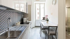 Een moderne keuken met een roestvrijstalen spoelbak, een magnetron en een raam met uitzicht op de straat.