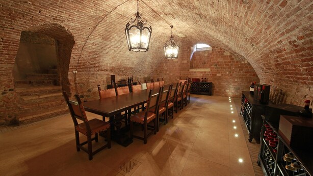 A brick-walled room with a long table and chairs, a wine rack, and a bar area. - Villa della Torre in Città (Verona)
