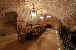 A brick-walled room with a long table and chairs, a wine rack, and a bar area. - Villa della Torre in Città (Verona)
