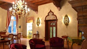 A traditional room with a chandelier, red upholstered chairs, a wooden table, and a decorative door with stained glass. - Villa della Torre in Città (Verona)